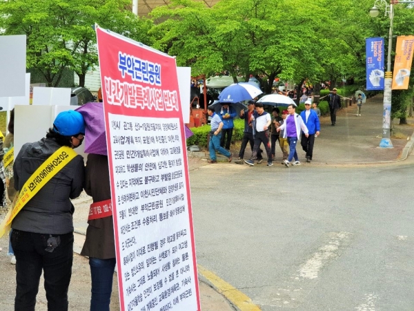 엄태준 이천시장이 19일 오전 설봉공원에서 열린 이천시민 한마음 걷기대회에 참석하기 위해 피켓시위대 맞은편을 지나가고 있다.